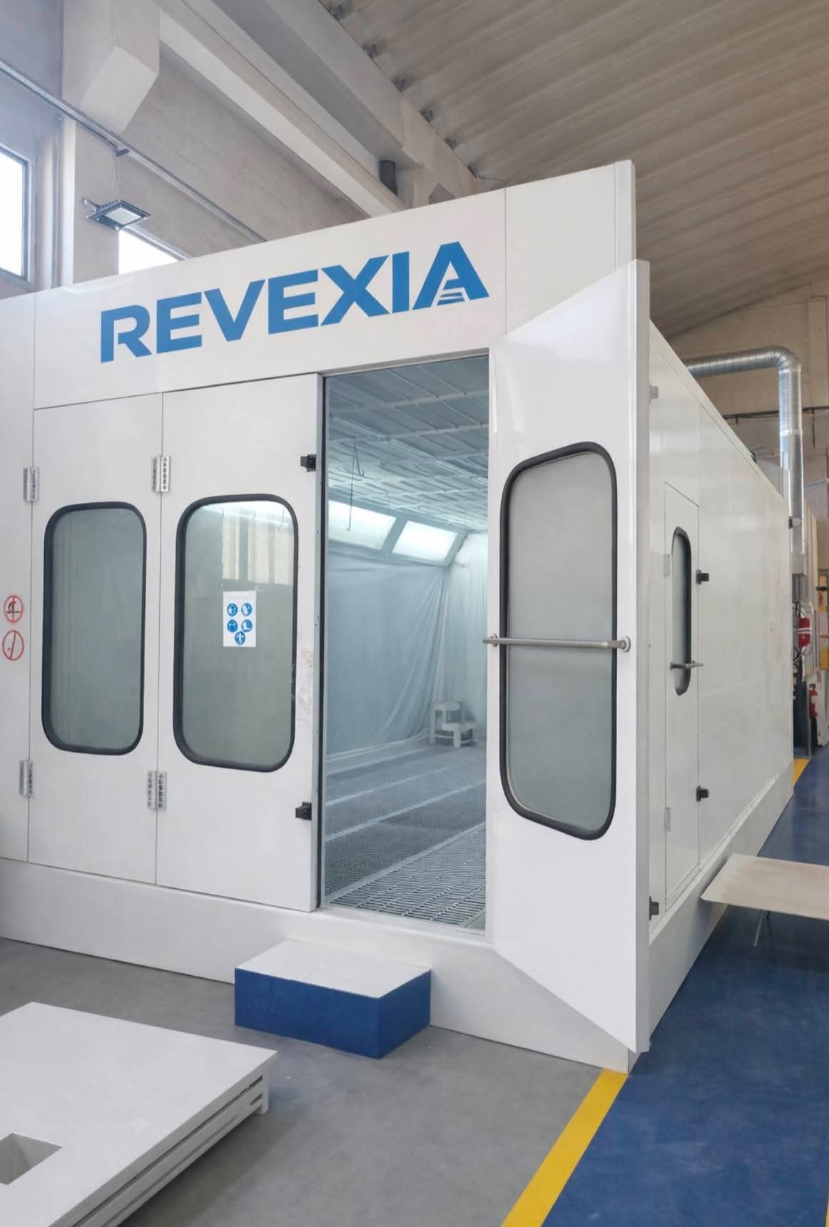 Cabine de peinture REVEXIA fermée avec portes vitrées dans un atelier